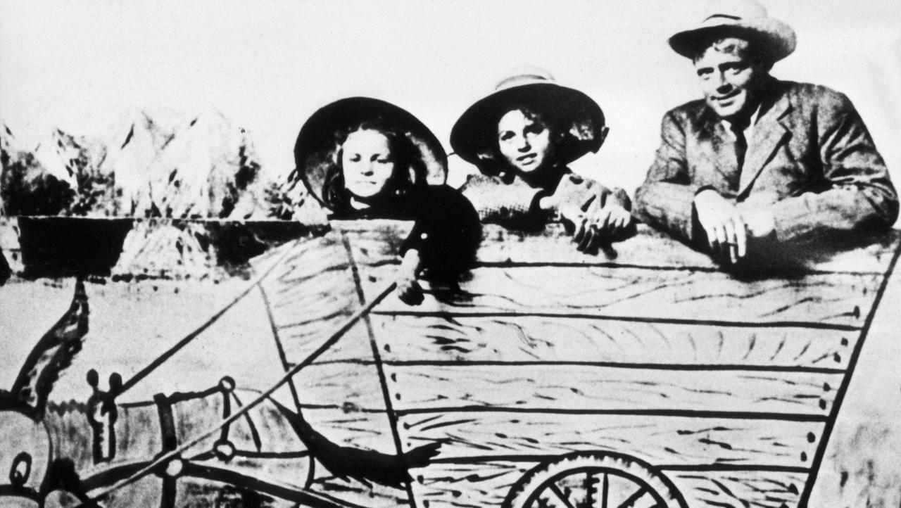 Der amerikanische Schriftsteller Jack London mit seinen beiden Töchtern Becky (l) und Joan auf einem Spaßbild mit einem gemalten Eselskarren (undatiert). Der amerikanische Schriftsteller Jack London mit seinen beiden Töchtern Becky (l) und Joan auf einem Spaßbild mit einem gemalten Eselskarren (undatiert).