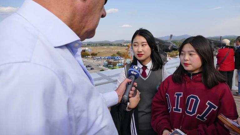 2 südkoreanische Schülerinnen sprechen in das Mikrofon des Reporters. 2 südkoreanische Schülerinnen sprechen in das Mikrofon des Reporters.