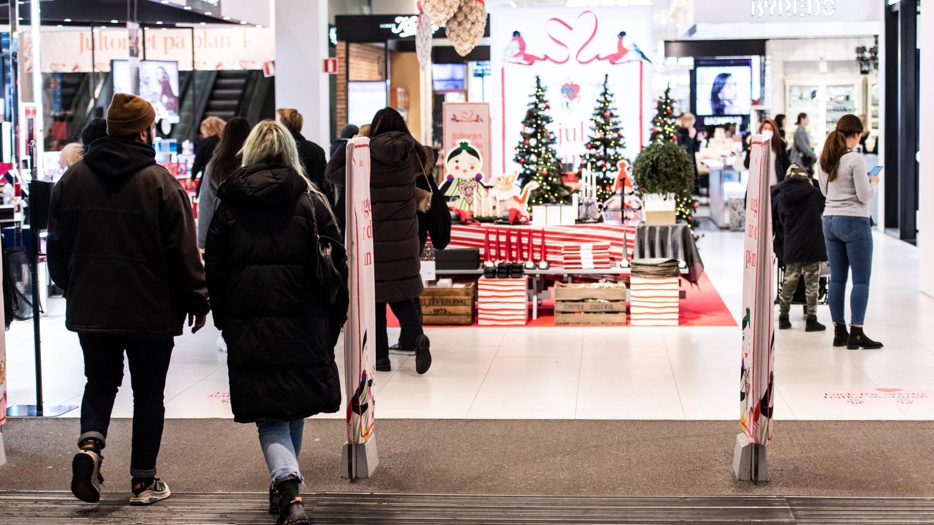 Kunden in einem weihnachtlich dekorierten Warenhaus in Stockholm tragen keinen Mund-Nasenschutz. Kunden in einem weihnachtlich dekorierten Warenhaus in Stockholm tragen keinen Mund-Nasenschutz.