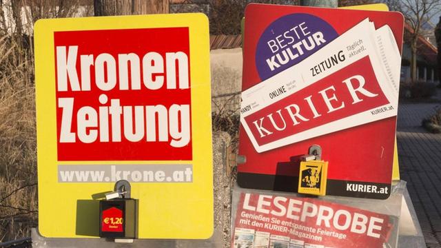 Werbung mit Leseproben für Kronen Zeitung und Kurier hängen an Pfählen.
