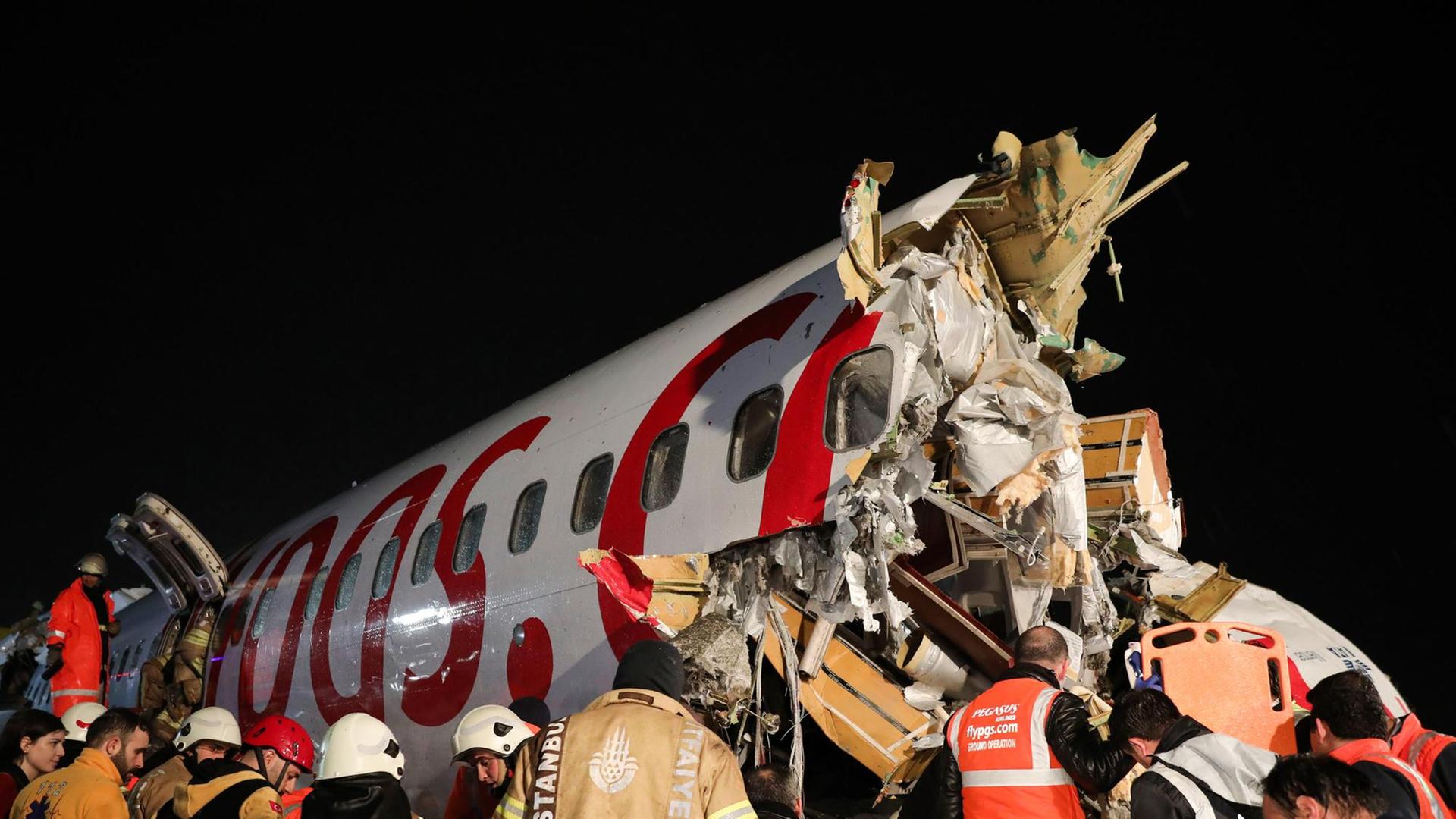Viele Rettungskräfte stehen in der Nacht um einen der abgerissenen Rumpfteile herum. Viele Rettungskräfte stehen in der Nacht um einen der abgerissenen Rumpfteile herum.