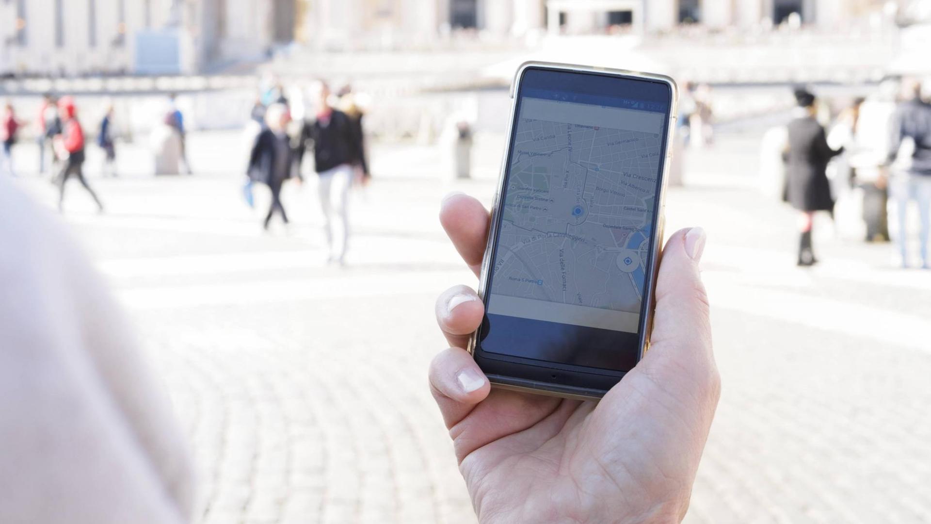 Eine Frau hält ein Smartphone mit der eingeschalteten GPS Funktion in der Hand. Sie befindet sich in Rom Eine Frau hält ein Smartphone mit der eingeschalteten GPS Funktion in der Hand. Sie befindet sich in Rom