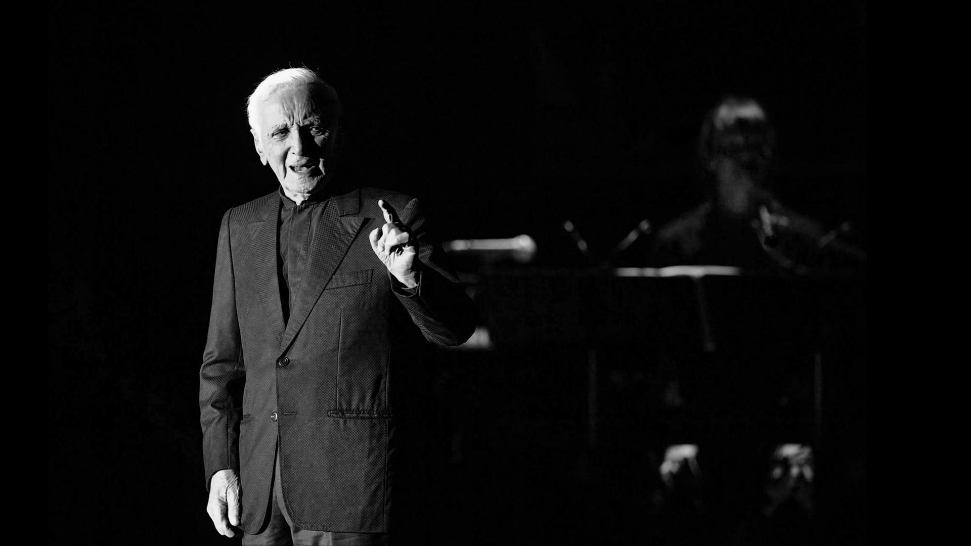 Ein schwarz-weiß Bild des französischen Sängers Charles Aznavour auf der Bühne während eines Konzerts in Prag. Ein schwarz-weiß Bild des französischen Sängers Charles Aznavour auf der Bühne während eines Konzerts in Prag.