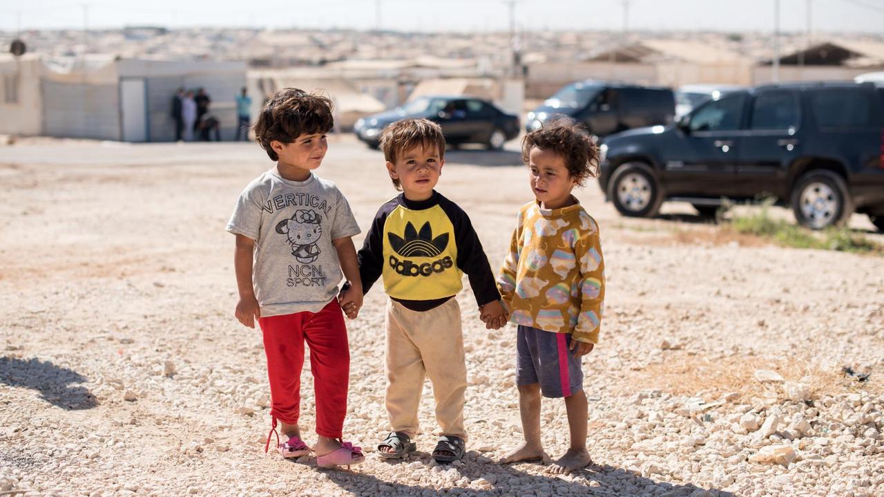 Flüchtlingskinder aus Syrien stehen im Flüchtlingslager Zaatari in Jordanien und schauen sich die deutsche Delegation an. 
