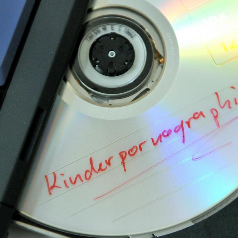 Ein Datenträger mit dem Schriftzug "Kinderpornographie" im CD-Laufwerk eines Laptops.