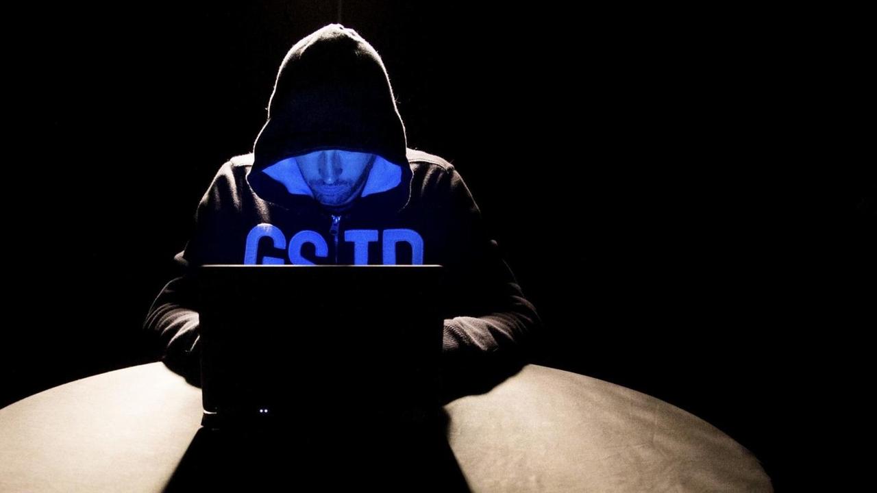 Ein Hacker mit Kapuzenpulli sitzt vor seinem Laptop. Ein Hacker mit Kapuzenpulli sitzt vor seinem Laptop.