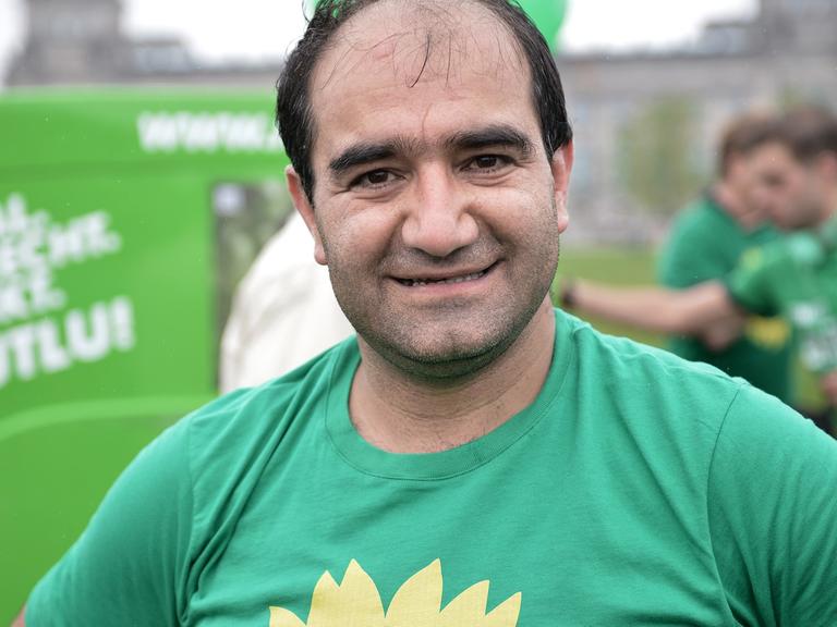 Özcan Mutlu von Bündnis 90/Die Grünen steht am 18.09.2013 auf einer Wiese vor dem Reichstagsgebäude in Berlin. Mit einem Lauf durch Berlin unter dem Motto "Endspurt zum Bundestag" haben Grünen-Kandidaten auf sich aufmerksam gemacht.