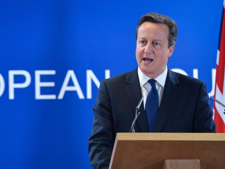 David Cameron spricht an einem Rednerpult, im Hintergrund die britische Flagge Union Jack