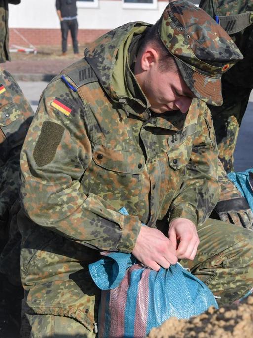 Bundeswehrsoldaten befüllen Sandsäcke während einer Katastrophenschutzübung.