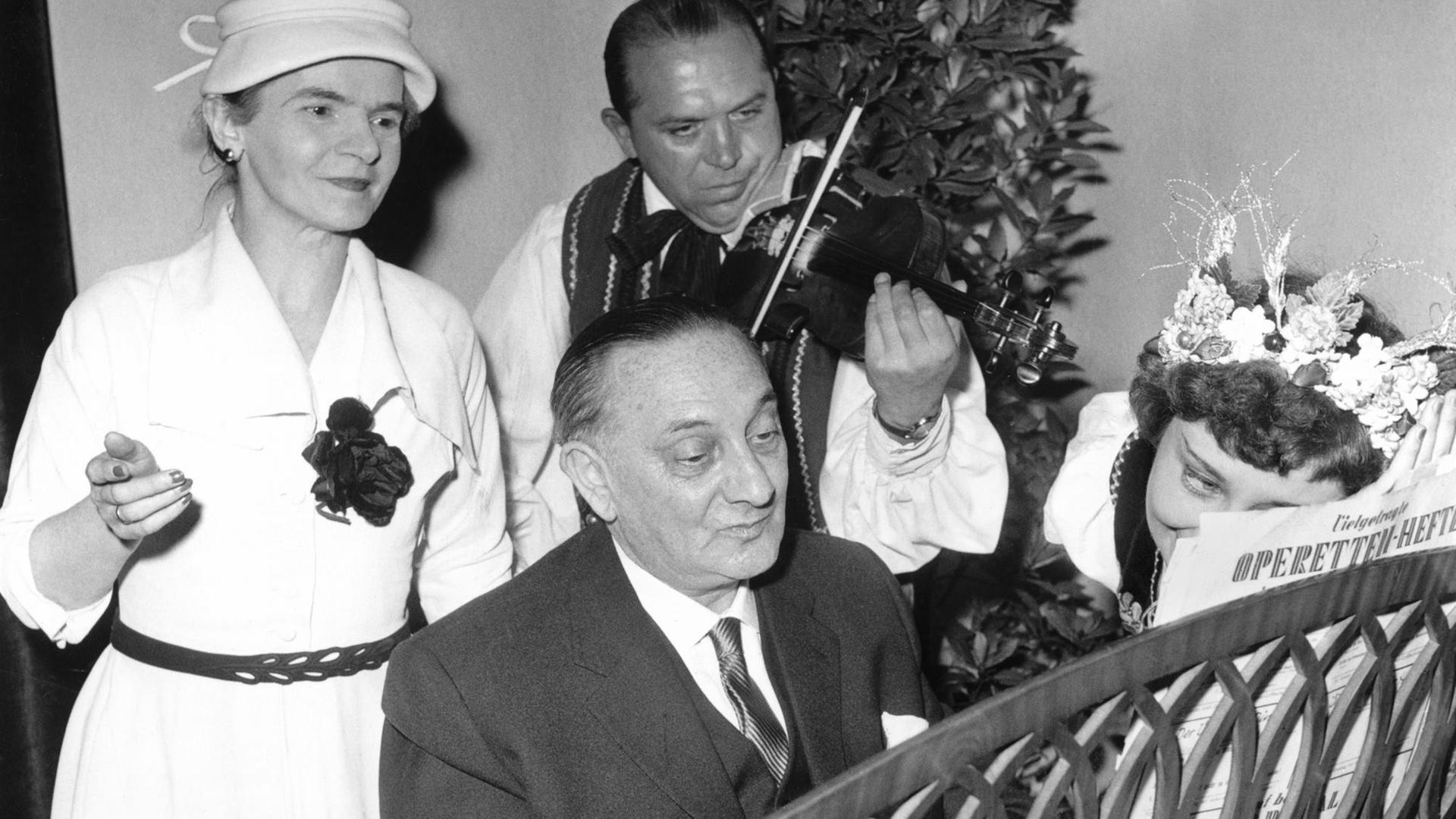 Der ungarische Operettenkomponist Paul Abraham musiziert am Blüthner-Flügel, rechts die ungarische Sängerin Piroska Litvay und ein Primus des Zigeunerorchesters, links die Gründerin des "Paul Abraham-Komitees" Frau Persich, die sich sehr für die Rückkehr Abrahams nach Deutschland einsetzte. Aufgenommen am 04.09.1956 in der Universitätsklinik Eppendorf in Hamburg. Der ungarische Operettenkomponist Paul Abraham musiziert am Blüthner-Flügel, rechts die ungarische Sängerin Piroska Litvay und ein Primus des Zigeunerorchesters, links die Gründerin des "Paul Abraham-Komitees" Frau Persich, die sich sehr für die Rückkehr Abrahams nach Deutschland einsetzte. Aufgenommen am 04.09.1956 in der Universitätsklinik Eppendorf in Hamburg.