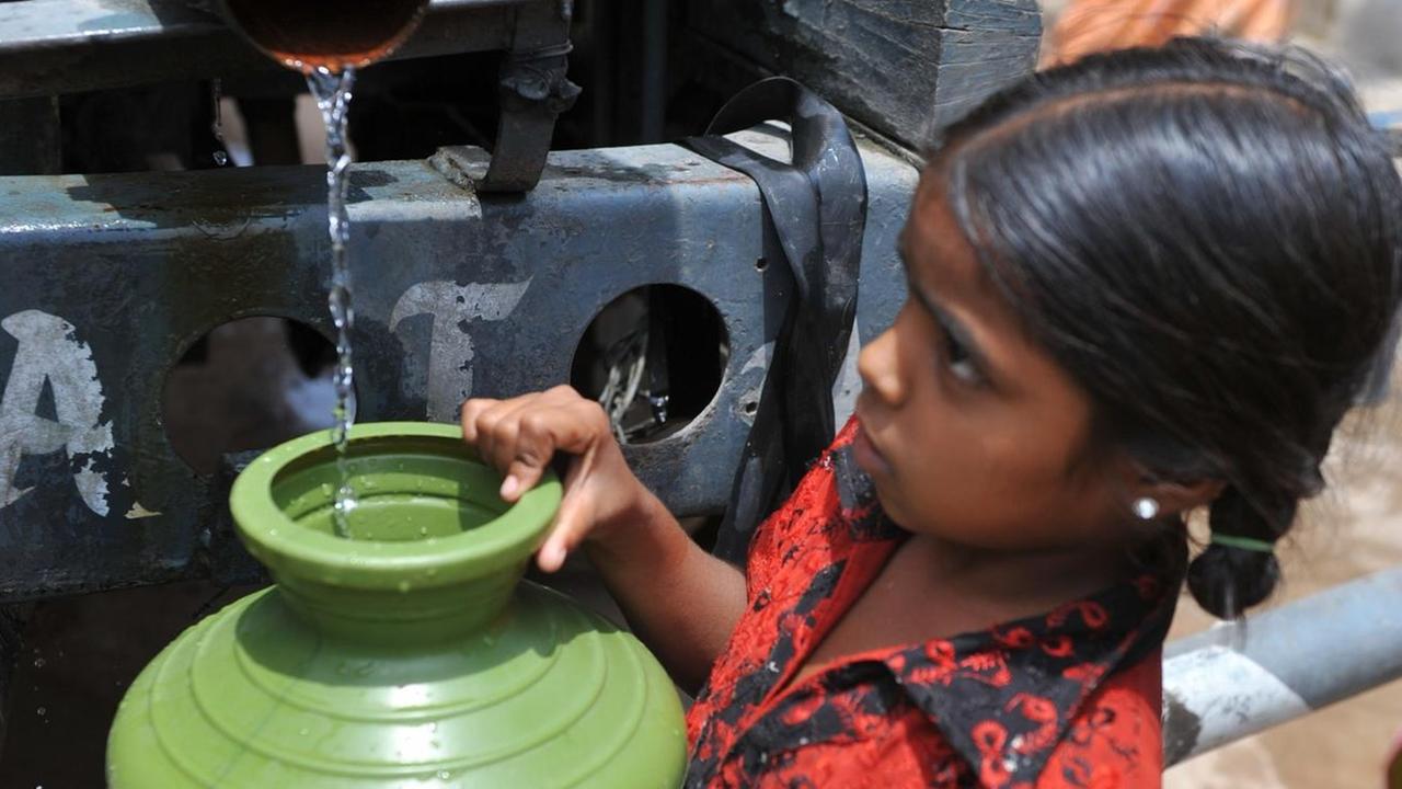 Ein indisches Mädchen füllt einen Krug mit Trinkwasser aus einem Tankwagen im Slum Rasoolpura in Hyderabad