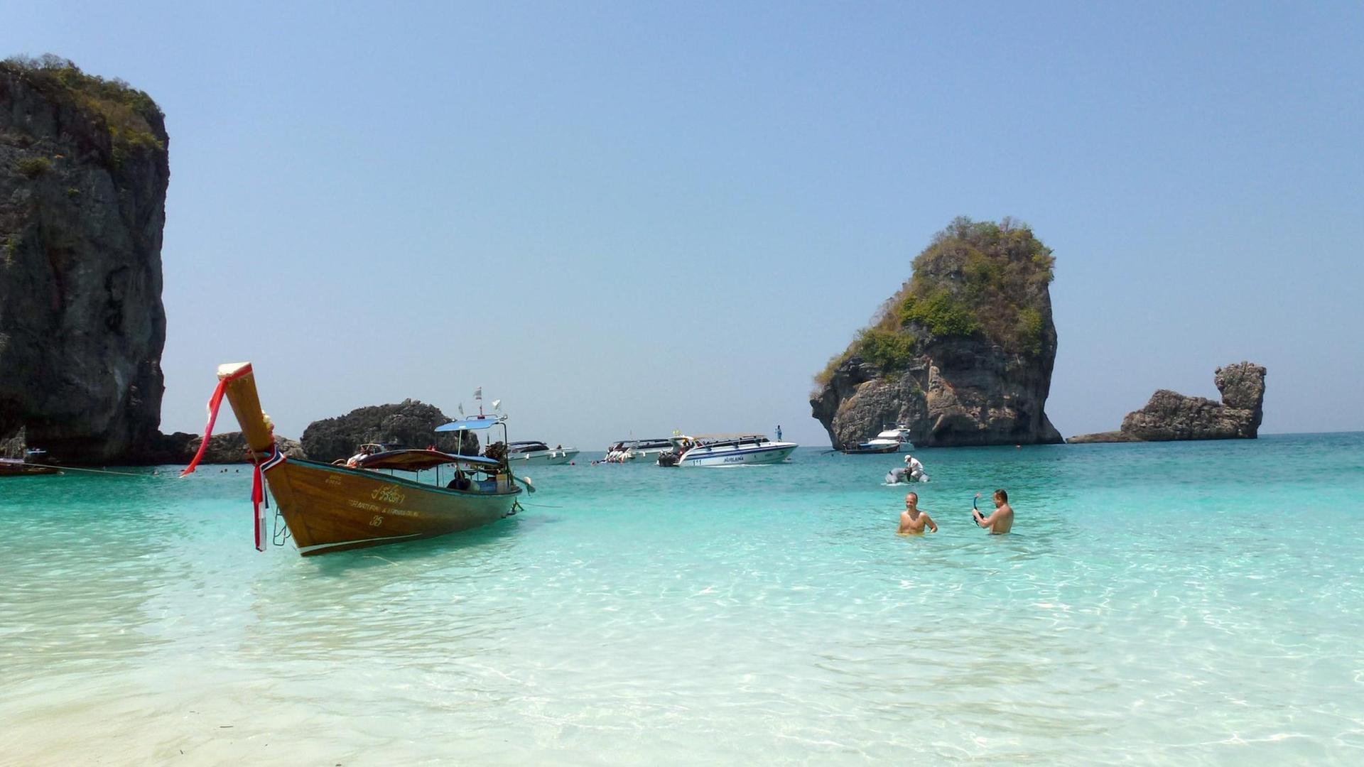 Ein Langheckboot und andere Boote liegen in der Nui Bay auf Ko Phi Phi Don, Thailand. Im Hintergrund rechts ist der "Camel Rock" zu sehen, der an die Form eines Kamels erinnert. Die Insel ist die größte Insel der thailändischen Ko-Phi-Phi-Inselgruppe. Foto: Alexandra Schuler Ein Langheckboot und andere Boote liegen in der Nui Bay auf Ko Phi Phi Don, Thailand. Im Hintergrund rechts ist der "Camel Rock" zu sehen, der an die Form eines Kamels erinnert. Die Insel ist die größte Insel der thailändischen Ko-Phi-Phi-Inselgruppe. Foto: Alexandra Schuler