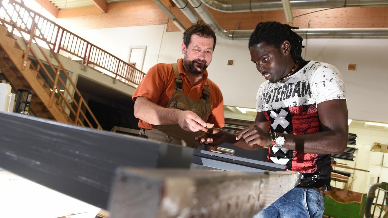 Omar Ceesay und Schreiner Karl-Heinz Kübler arbeiten an einem Türrahmen. Omar Ceesay und Schreiner Karl-Heinz Kübler arbeiten an einem Türrahmen.