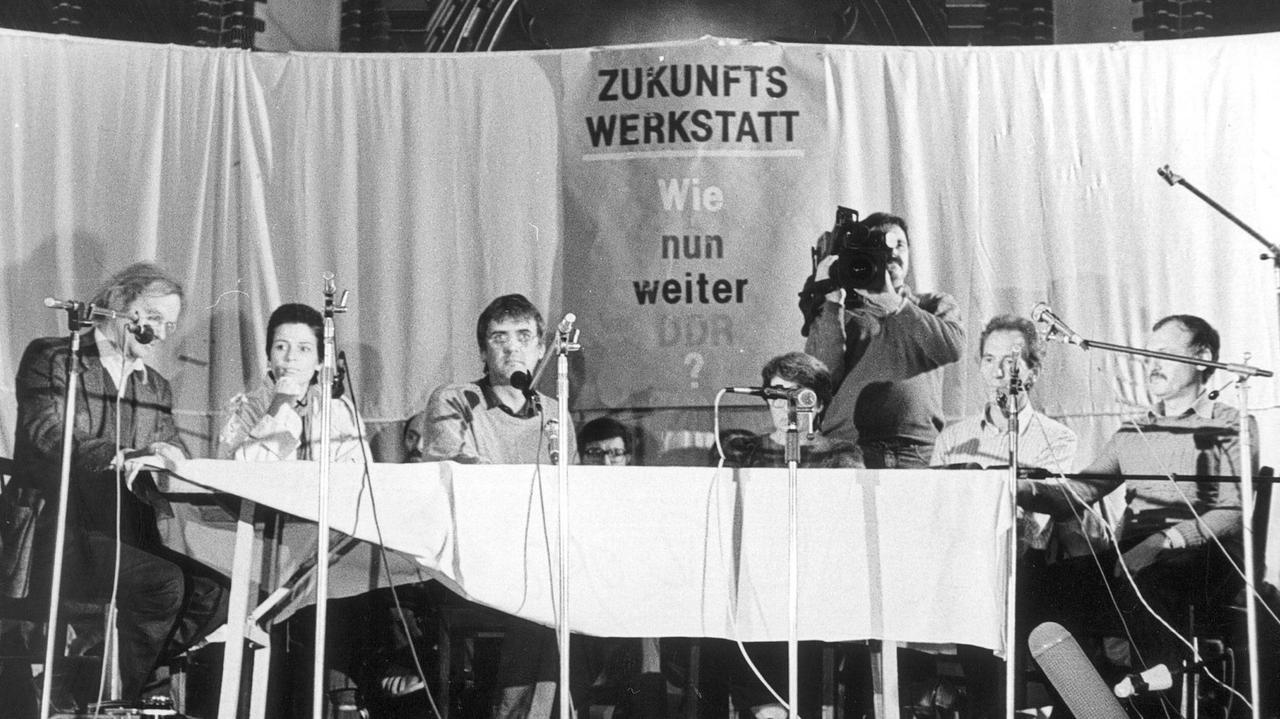 Zu einer Zukunftswerkstatt unter dem Thema "Wie nun weiter DDR?" hatte am 06.10.1989 das evangelische Stadtjugendpfarramt in die Ost-Berliner Erlöserkirche eingeladen. Mehrere Menschen sitzen auf einer Bühne. Zu einer Zukunftswerkstatt unter dem Thema "Wie nun weiter DDR?" hatte am 06.10.1989 das evangelische Stadtjugendpfarramt in die Ost-Berliner Erlöserkirche eingeladen. Mehrere Menschen sitzen auf einer Bühne.