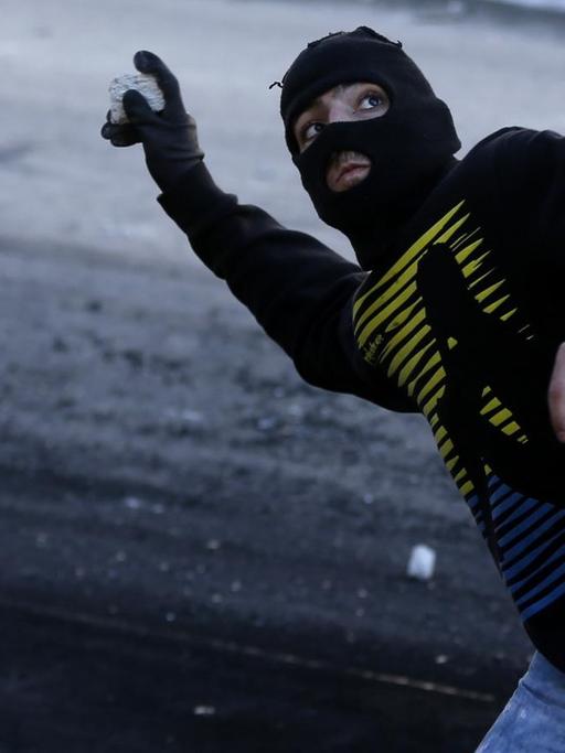 Ein palästinensischer Jugendlicher wirft einen Stein.