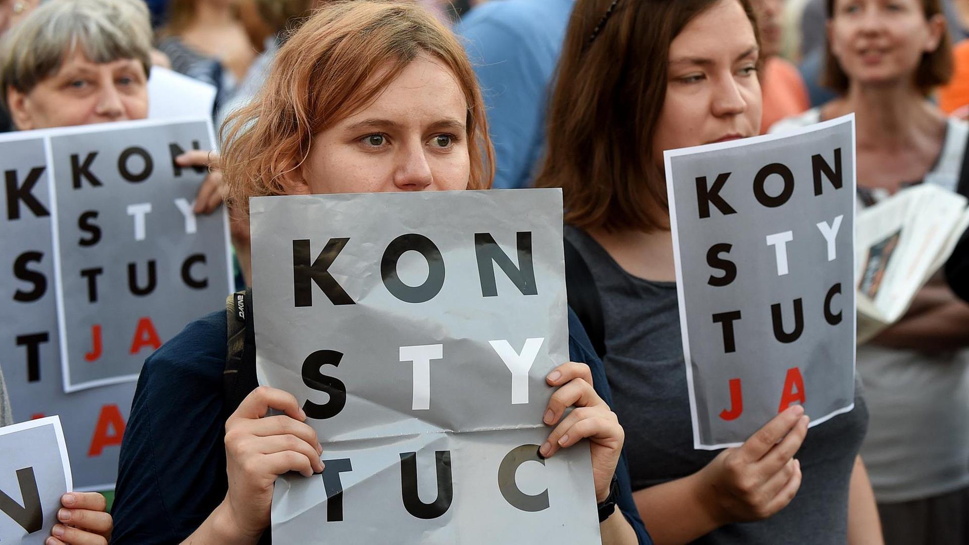 Demonstranten halten am 23.7.2017 vor dem Präsidentenpalast in Warschau Poster mit der Aufschrift "Verfassung" (auf Polnisch) in die Höhe. Demonstranten halten am 23.7.2017 vor dem Präsidentenpalast in Warschau Poster mit der Aufschrift "Verfassung" (auf Polnisch) in die Höhe.