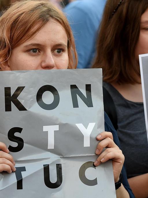 Polen, die gegen die Justizreform auf die Straße gegangen sind und Protestplakate hochhalten. 