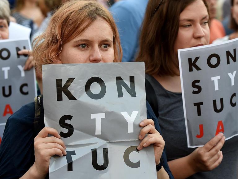 Polen, die gegen die Justizreform auf die Straße gegangen sind und Protestplakate hochhalten. 
