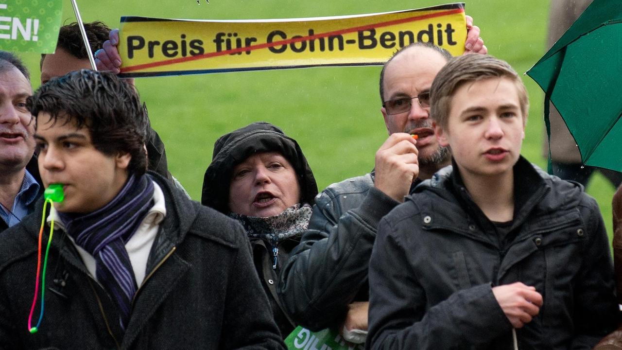 Demonstranten protestieren am 20.04.2013 auf dem Schlossplatz in Stuttgart (Baden-Württemberg) vor Beginn der Verleihung des Theodor-Heuss-Preises an den Grünen-Europapolitiker und Publizisten Daniel Cohn-Bendit. Rund 70 Vertreter eines Opfer-Verbandes und die Junge Union haben am Samstag gegen die Preisverleihung an Cohn-Bendit protestiert. Foto: Marijan Murat/dpa | Verwendung weltweit Demonstranten protestieren am 20.04.2013 auf dem Schlossplatz in Stuttgart (Baden-Württemberg) vor Beginn der Verleihung des Theodor-Heuss-Preises an den Grünen-Europapolitiker und Publizisten Daniel Cohn-Bendit. Rund 70 Vertreter eines Opfer-Verbandes und die Junge Union haben am Samstag gegen die Preisverleihung an Cohn-Bendit protestiert. Foto: Marijan Murat/dpa | Verwendung weltweit