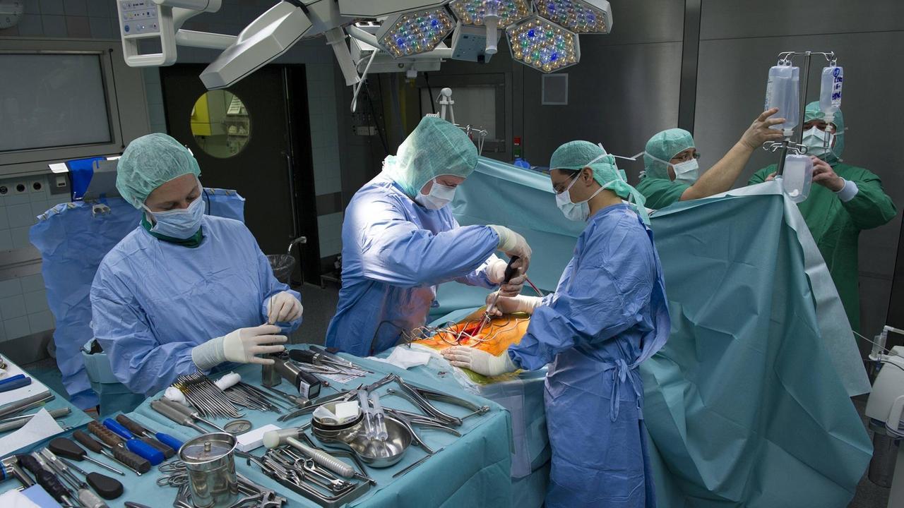 Ärzte operieren einen Patienten wegen einer Versteifung der Wirbelsäule in einem OP-Saal. Ärzte operieren einen Patienten wegen einer Versteifung der Wirbelsäule in einem OP-Saal.