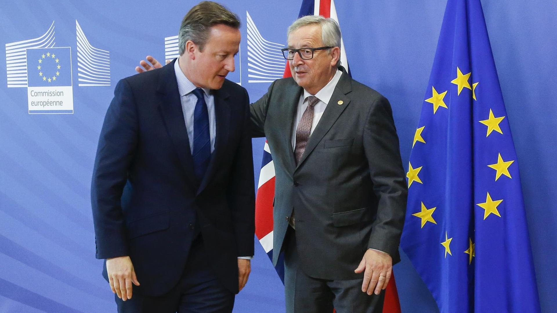 Jean-Claude Juncker klopft David Cameron vor einer EU-Flagge auf den Rücken Jean-Claude Juncker klopft David Cameron vor einer EU-Flagge auf den Rücken