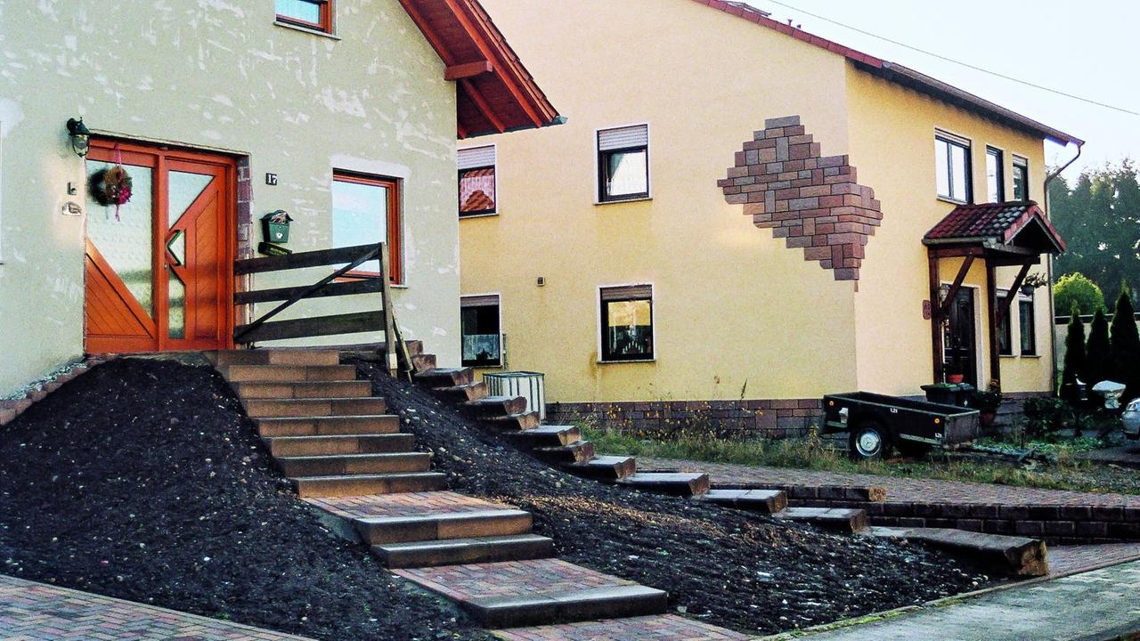 Einfamilienhaus mit einer Treppe auf einem aufgeschütteten Hügel, der zur Eingangstür führt. Einfamilienhaus mit einer Treppe auf einem aufgeschütteten Hügel, der zur Eingangstür führt.