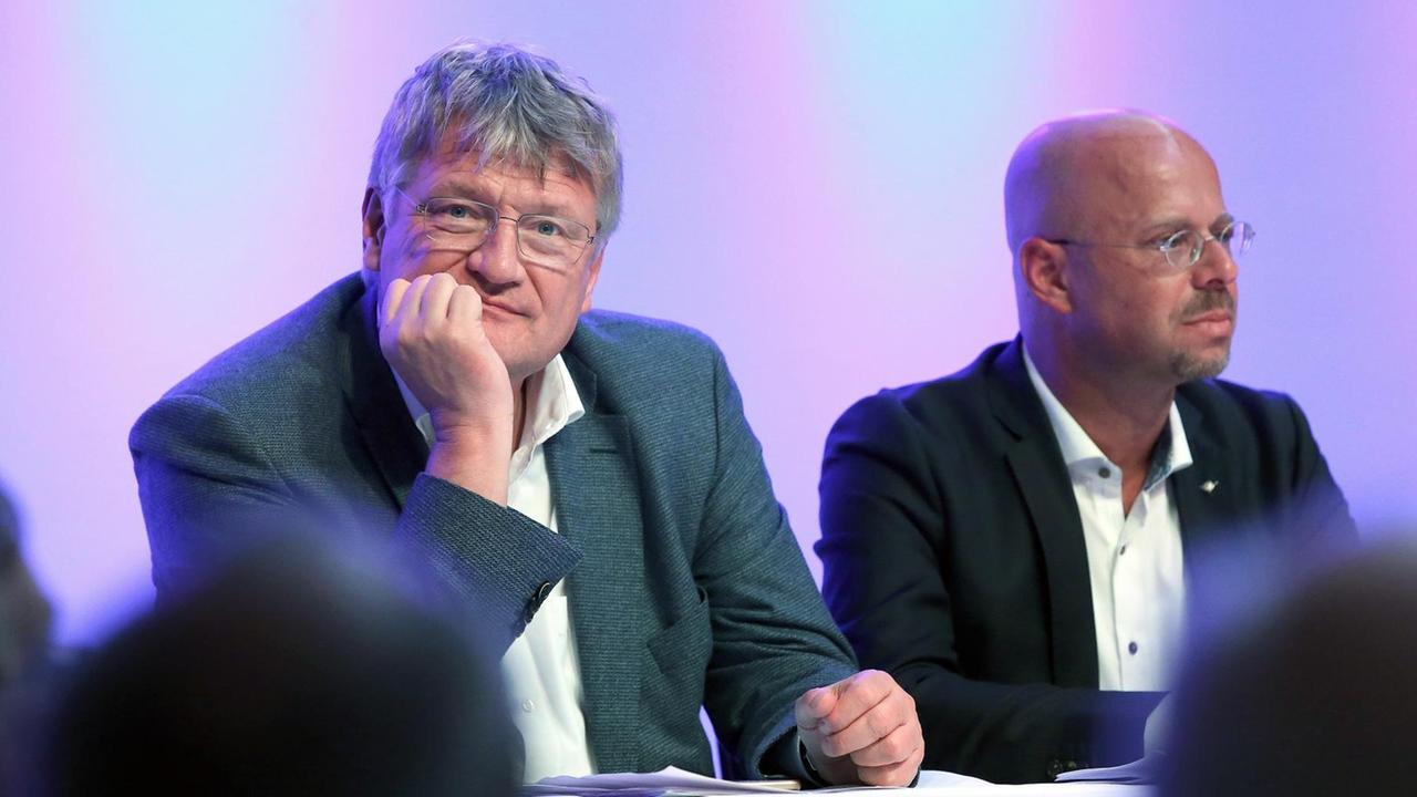 Jörg Meuthen und Andreas Kalbitz sitzen sitzen hinter einem Pult und blicken in unterschiedliche Richtungen.