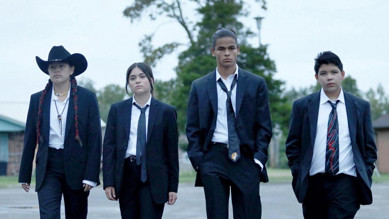 Die vier Protaginisten der Serie laufen nebeneinander, in dunklen Anzügen eine Straße entlang. Die vier Protaginisten der Serie laufen nebeneinander, in dunklen Anzügen eine Straße entlang.