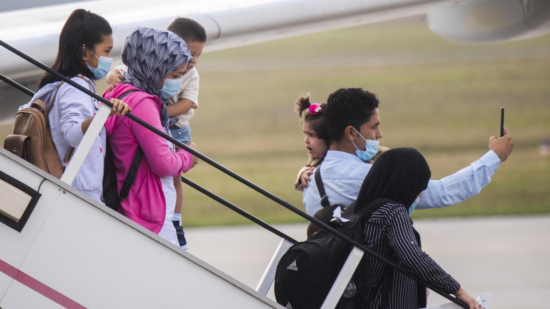 Migranten steigen aus dem Flugzeug aus.