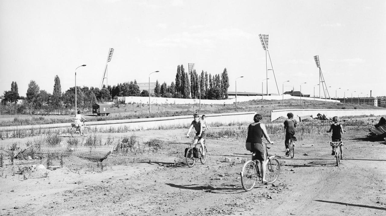 Radfahrer auf der Brachfläche am ehemaligen Mauerstreifen; im Hintergrund der Friedrich-Ludwig-Jahn-Sportpark. Radfahrer auf der Brachfläche am ehemaligen Mauerstreifen; im Hintergrund der Friedrich-Ludwig-Jahn-Sportpark.