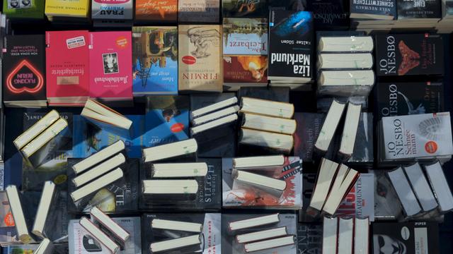 Eine Hand greift nach einem Buch auf einem Büchertisch in Leipzig.