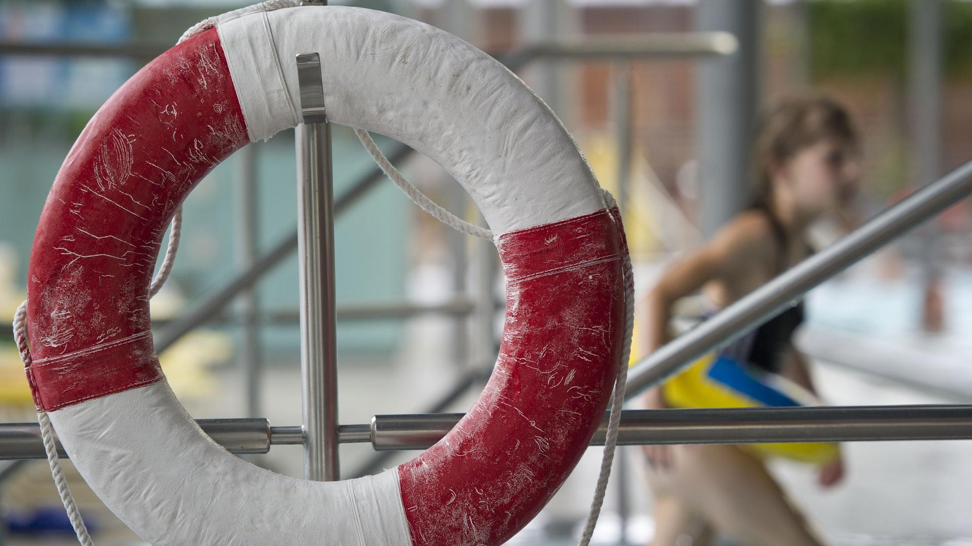 Ein Kind mit Schwimmring geht im Geibeltbad in Pirna (Sachsen) an einem Rettungsring vorbei. Ein Kind mit Schwimmring geht im Geibeltbad in Pirna (Sachsen) an einem Rettungsring vorbei.
