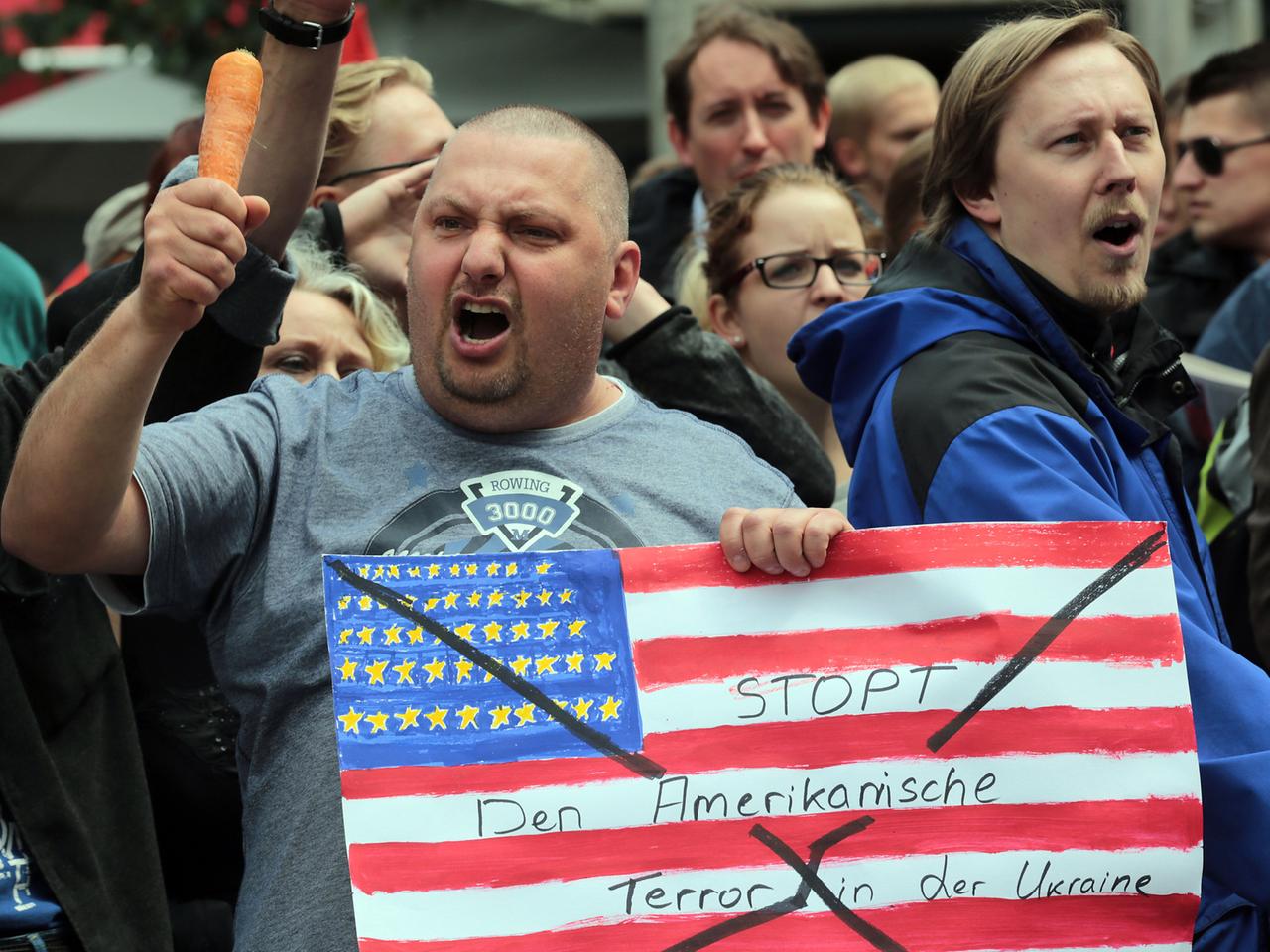 Mit einer Möhre in der Hand protestiert am 28.05.2014 in Aachen (Nordrhein-Westfalen) während der Verleihung des Karlspreises ein Mann gegen den Einfluss der USA in der Ukraine.