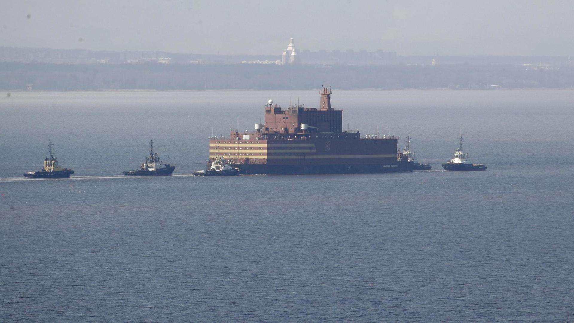 Das Bild zeigt das umstrittene "Schwimmende Atomkraftwerk" Russlands, die "Akademik Lomonossow", die hier im Wasser von Beibooten eskortiert wird.