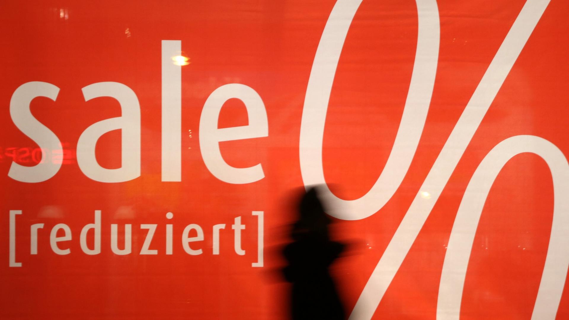 Ein Mensch geht an einer Sale-Werbung vorbei. Ein Mensch geht an einer Sale-Werbung vorbei.