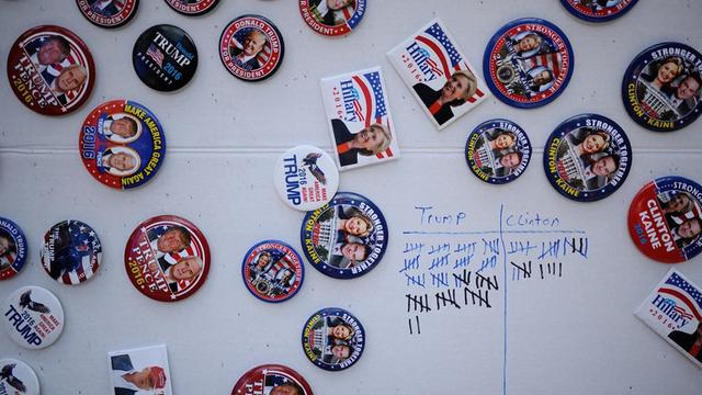 Magnete der Demokraten und der Republikaner kleben an einer Wand, daneben eine Strichliste über verkaufte Buttons.