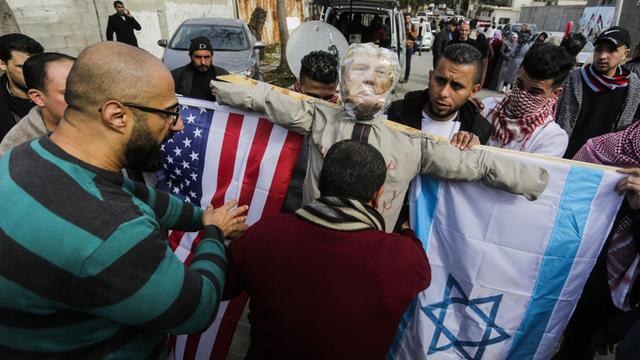 Demonstranten im Gazastreifen tragen während eines Protestes eine als US-Präsident Trump verkleidete Strohpuppe, an deren Armen eine israelische und eine US-amerikanische Flagge hängen.