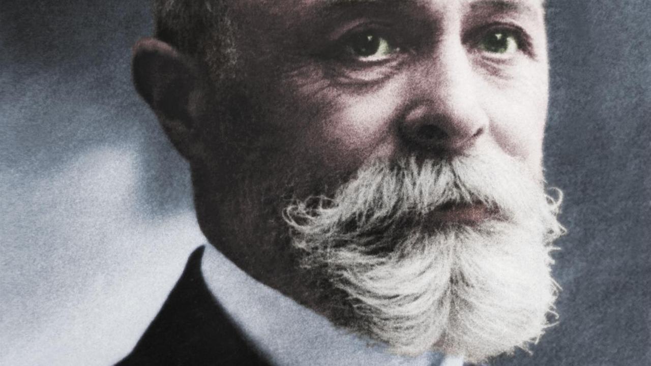 Die digitale Kolorierung eines Schwarzweiß-Fotos von 1903 zeigt den französischen Physiker Henri Becquerel mit weißen Vollbart, Glatze, und dunkelblauem Jackett über grüner Weste. Die digitale Kolorierung eines Schwarzweiß-Fotos von 1903 zeigt den französischen Physiker Henri Becquerel mit weißen Vollbart, Glatze, und dunkelblauem Jackett über grüner Weste.