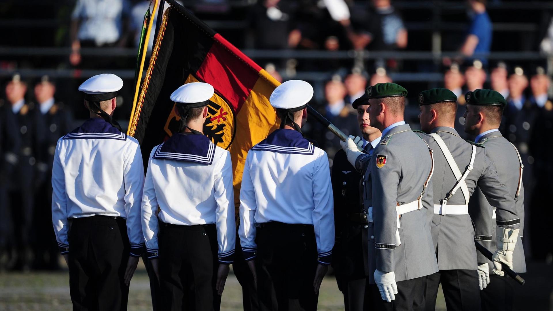 Rückenansicht von Bundeswehr- und Marinesoldaten mit leicht verdeckter Deutschlandfahne.