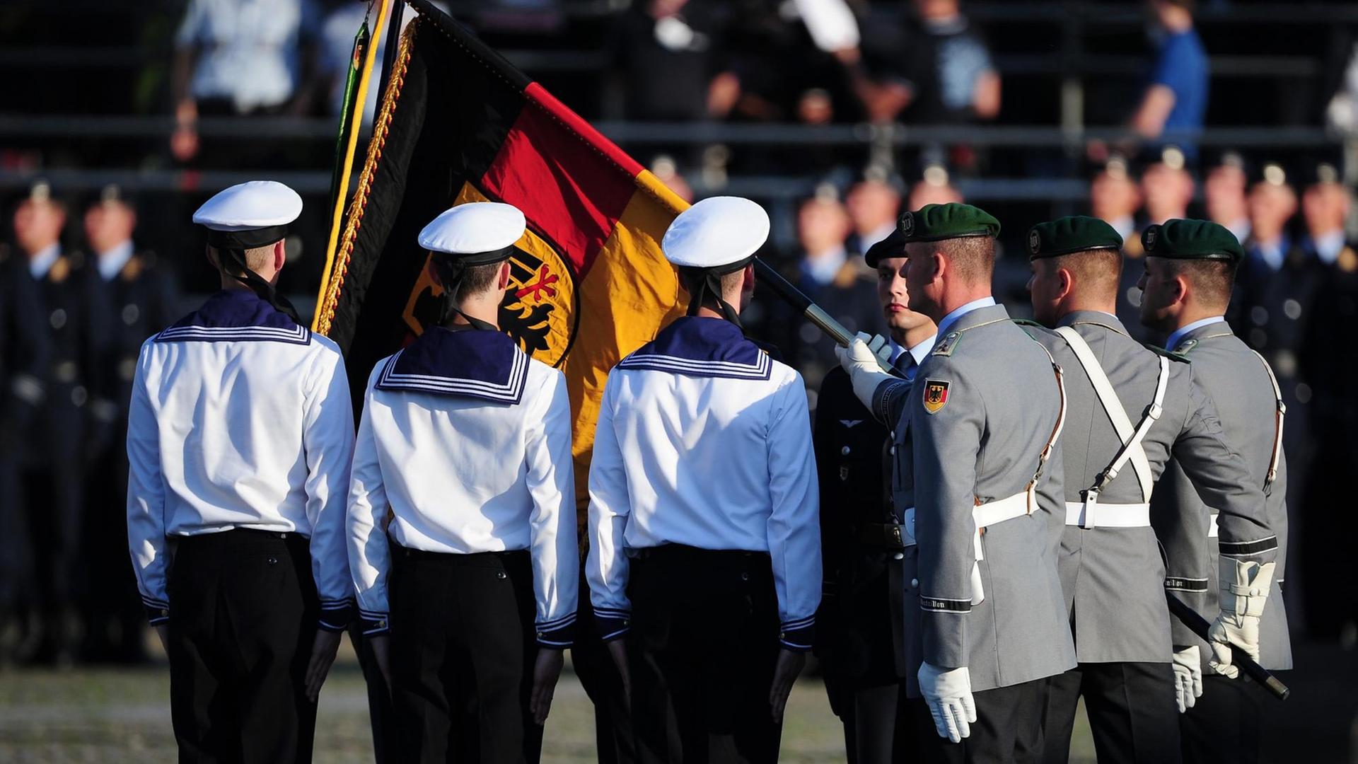 Rückenansicht von Bundeswehr- und Marinesoldaten mit leicht verdeckter Deutschlandfahne. Rückenansicht von Bundeswehr- und Marinesoldaten mit leicht verdeckter Deutschlandfahne.