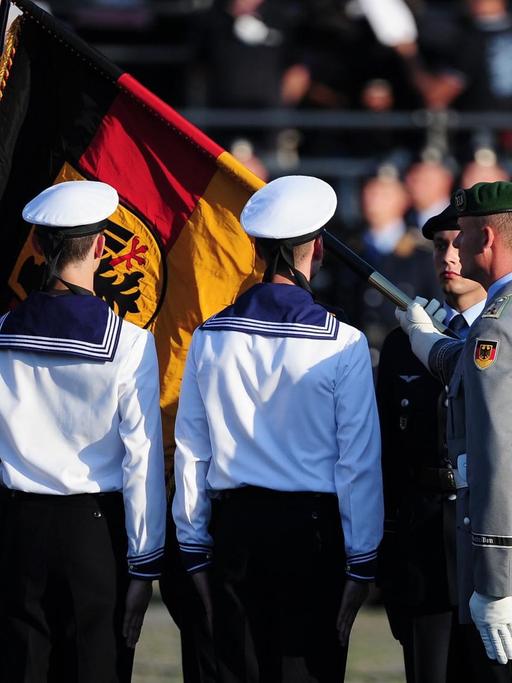 Rückenansicht von Bundeswehr- und Marinesoldaten mit leicht verdeckter Deutschlandfahne.