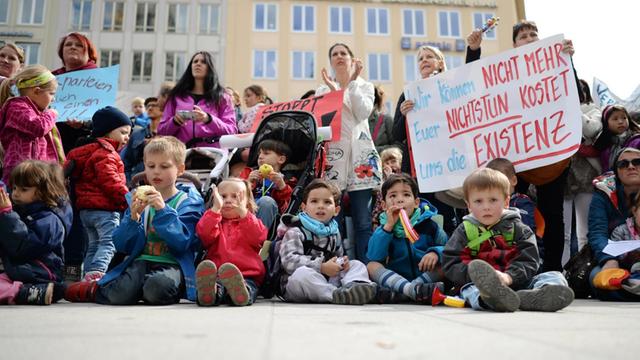 Eine Kundgebung von Eltern und Kindern gegen den Kita-Streik in München. Zwei Teilnehmerinnen halten ein Plakat mit der Aufschrift "Wir können nicht mehr. Euer Nichtstun kostet uns die Existenz" in Händen.