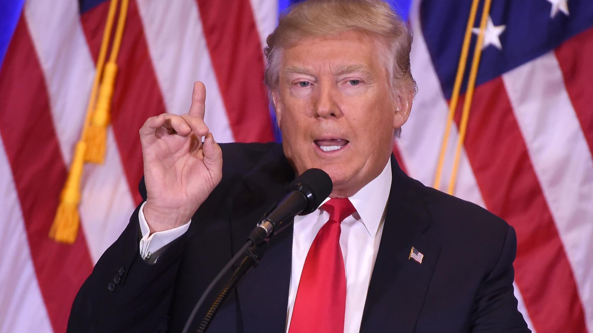 Donald Trump steht bei seiner ersten Pressekonferenz am 11.01.2017 im New Yorker Trump Tower mit erhobenem Zeigefinger vor mehreren US-Flaggen. Donald Trump steht bei seiner ersten Pressekonferenz am 11.01.2017 im New Yorker Trump Tower mit erhobenem Zeigefinger vor mehreren US-Flaggen.