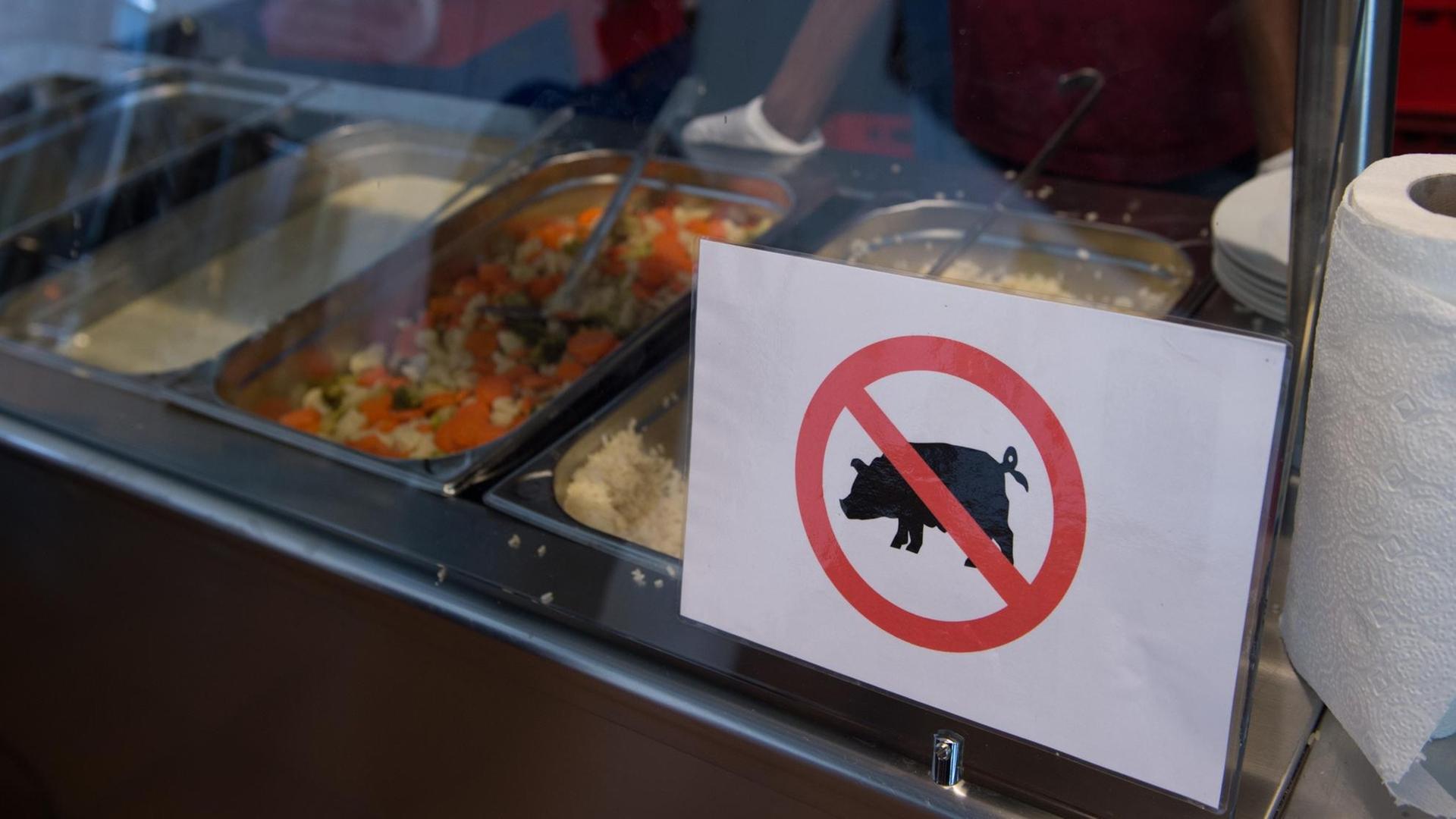 Ein Schild mit einem durchgestrichenen Schwein an einer Kantinentheke. Ein Schild mit einem durchgestrichenen Schwein an einer Kantinentheke.