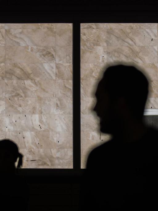 Die schwarzen Silhouetten eines Mannes und einer Frau sind durch ein Fenster zu sehen.