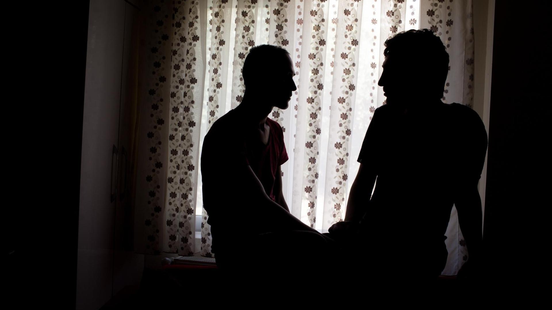 Die Schatten der Partner Danial und Parsa vor einem hellen Fenstervorhang. Die Schatten der Partner Danial und Parsa vor einem hellen Fenstervorhang.