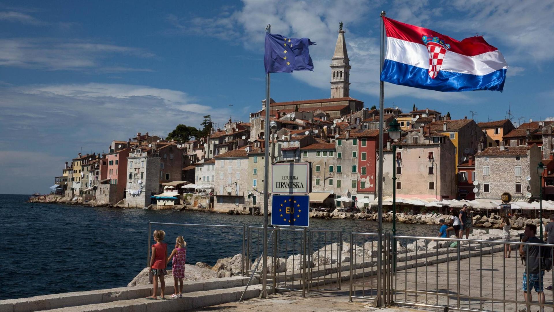 Die Fahnen der EU und von Kroatien wehen an einer Hafeneinfahrt in Rovinj, Istrien, Kroatien.
