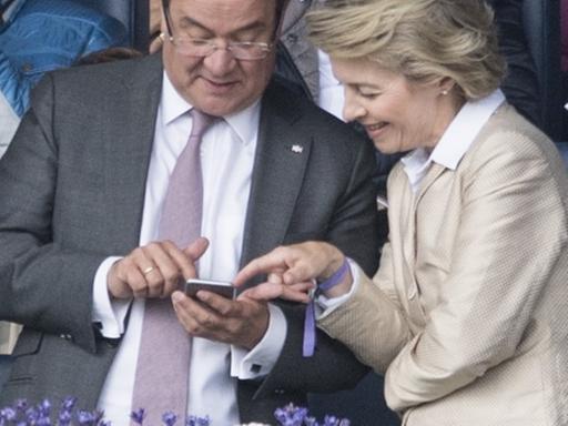 Der Ministerpräsident von Nordrhein-Westfalen, Armin Laschet, und die damalige Bundesverteidigungsministerin Ursula von der Leyen schauen auf ein Handy.