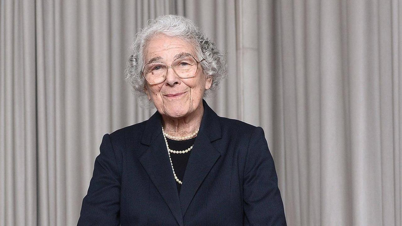 Judith Kerr steht hinter einem großen Ledersessel und lächelt in die Kamera. Judith Kerr steht hinter einem großen Ledersessel und lächelt in die Kamera.