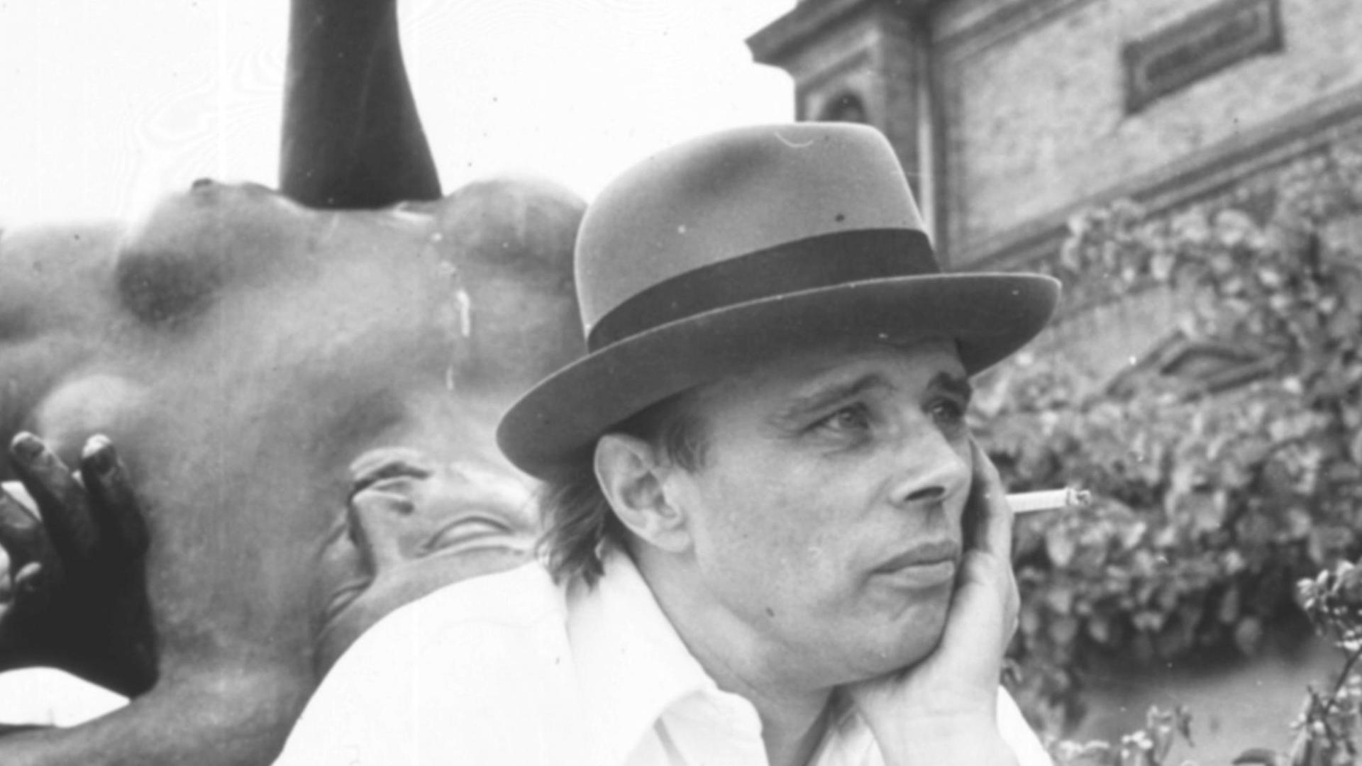 Joseph Beuys sitzt vor der Bleiplastik „Der Fluss“ von Aristide Maillol vor der Hamburger Kunsthalle und raucht eine Zigarette Joseph Beuys sitzt vor der Bleiplastik „Der Fluss“ von Aristide Maillol vor der Hamburger Kunsthalle und raucht eine Zigarette